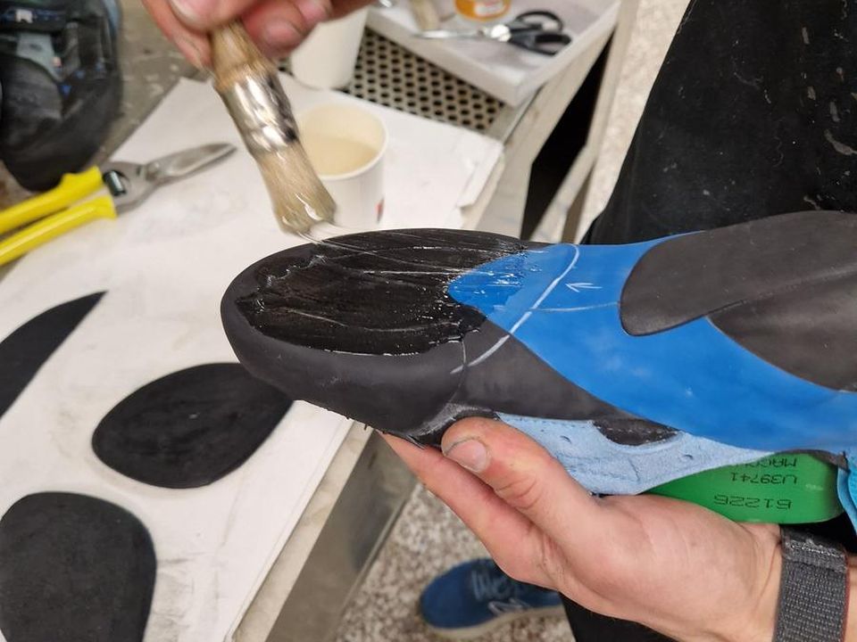 Stesura della colla sulla suola durante una risuolatura